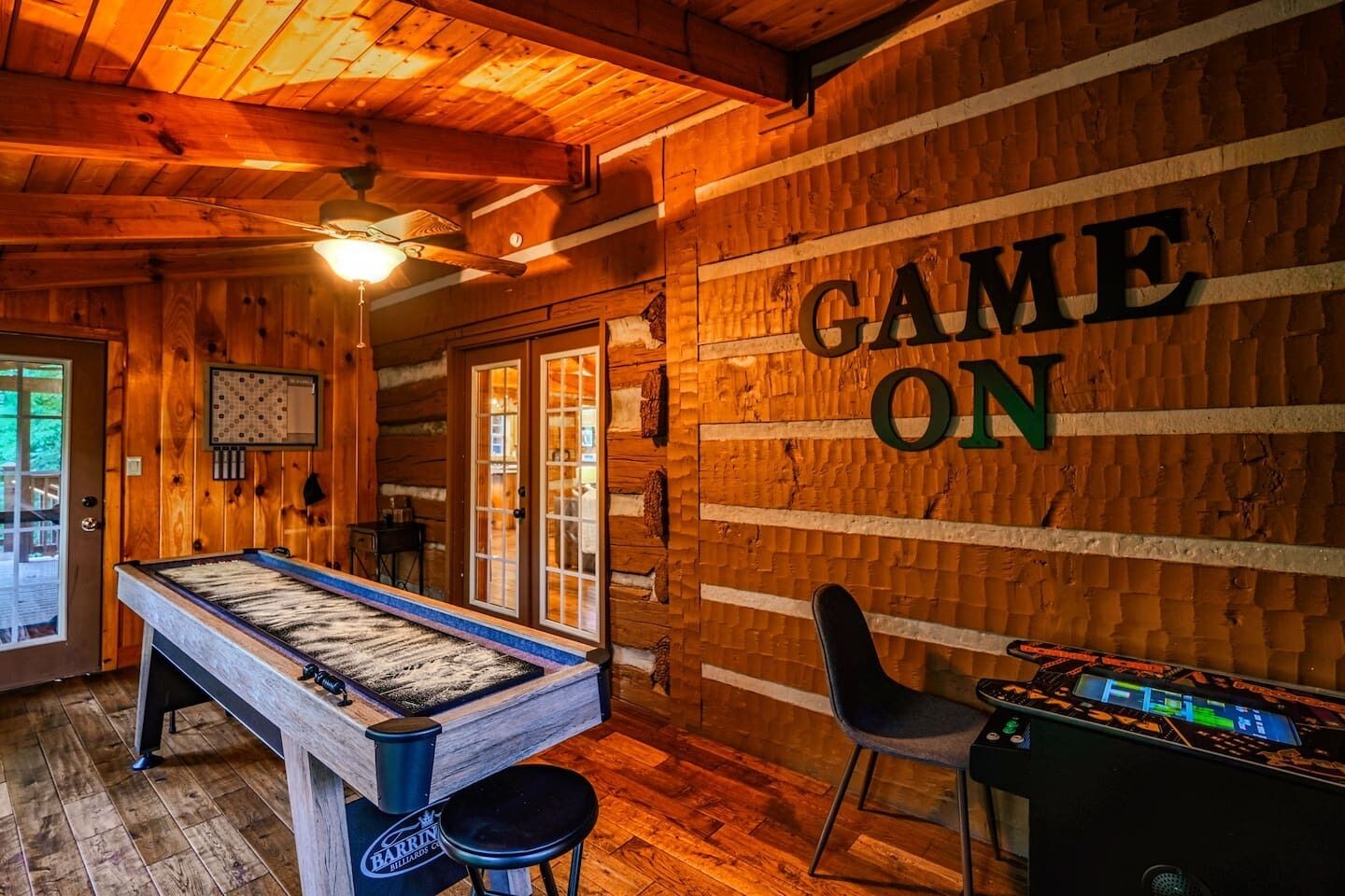 A wooden interior with a pool table, a foosball table, and a sign that reads "GAME ON".
