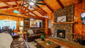 A cozy cabin interior with a stone fireplace, leather furniture, and wooden beams. - Private, 1 mile to Downtown, Hot Tub, Firepit (Gatlinburg)