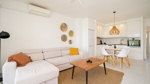 A modern living room with a sofa, coffee table, and a dining area with chairs and a table.