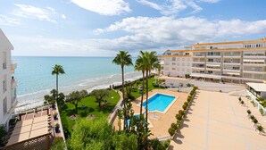 A resort with a pool, palm trees, and a view of the ocean.