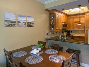 A dining table with placemats, chairs, and a plant centerpiece. - Gorgeous Ground Floor Condo in World Class Resort, Pool, Spa, Amenities Galore! (Naples)