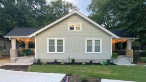 A single-story house with a front porch, a small deck, and a flag in the front yard. - Greer Twin Cottage A - Walk to City Park and Downtown Greer (Greer)