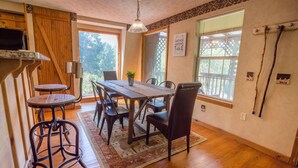 A dining area with a wooden table, chairs, and a rug. - Rock Right Inn* Cozy /Mtn Views*Creek*Firepit*Hot tub*1.5 acres* 4bed/2 bed*8-10 (Cosby)
