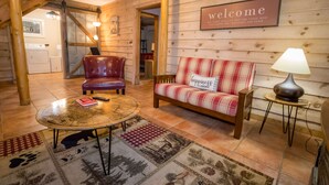 A cozy room with a plaid sofa, a red chair, a round coffee table, and a welcome sign. - Rock Right Inn* Cozy /Mtn Views*Creek*Firepit*Hot tub*1.5 acres* 4bed/2 bed*8-10 (Cosby)