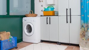 Une buanderie équipée d’un lave-linge, de placards et d’un panier posé sur les placards.