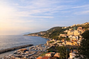 A coastal town with a marina, buildings on a hillside, and a clear view of the sea.