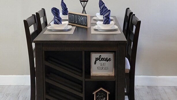 Una mesa de comedor preparada con platos, servilletas y un cartel que dice "FOOD & FRIENDS".