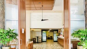 Un hall d’entrée avec un sol carrelé en pierre, des portes en bois et des plantes en pot.