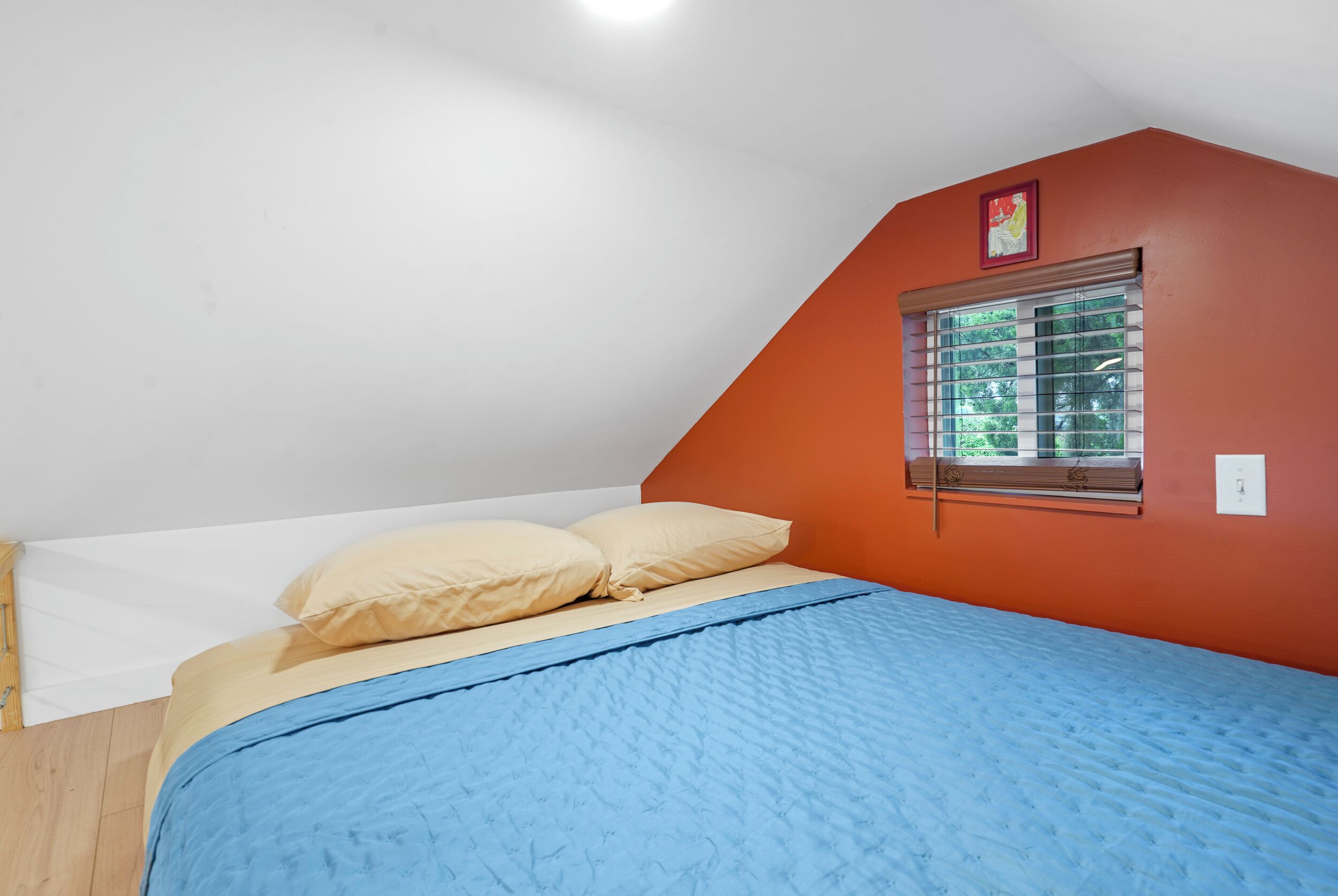 Ein Schlafzimmer mit einem Bett, einem Fenster mit Jalousien und einer roten Wand.