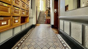 Un couloir avec des armoires en bois, un sol carrelé et un escalier menant à une pièce où se trouve un sapin de Noël.