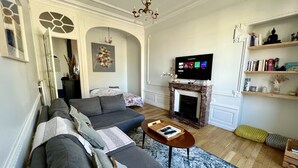 Un salon comprenant un canapé, une table basse, une cheminée, un téléviseur et une bibliothèque.