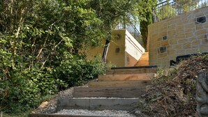 A stone staircase leading up to a building with a metal railing, surrounded by greenery. - Large apartment with terrace and pool view (La Bouilladisse)