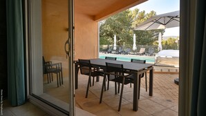 A patio with a table and chairs, a pool, and umbrellas in the background. - Large apartment with terrace and pool view (La Bouilladisse)