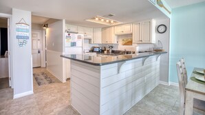 Una cocina moderna con armarios blancos, una isla central y un comedor con una mesa de madera.