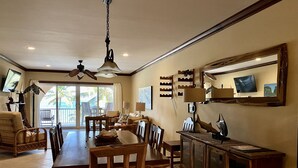 A spacious dining area with a wooden table and chairs, a ceiling fan, and a television mounted on the wall. - Oceanaire 4 - Amazing Oceanfront Views & Free use of Kayaks (San Pedro)
