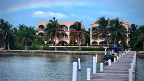 A waterfront hotel with a wooden dock extending into calm water, surrounded by palm trees and a clear sky. - Oceanaire 4 - Amazing Oceanfront Views & Free use of Kayaks (San Pedro)