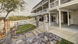 A multi-level building with a covered outdoor area, stone steps, and a white fence.