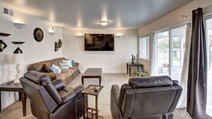 A living room with a brown leather sofa, a coffee table, and a TV mounted on the wall.