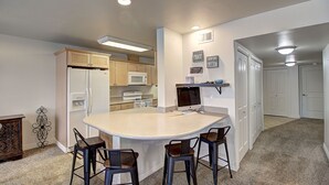 A kitchen with a central island, bar stools, a microwave, and a refrigerator.
