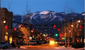 Une rue illuminée de guirlandes festives, avec une montagne en arrière-plan.