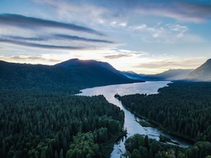 A river winding through a dense forest with mountains in the background.