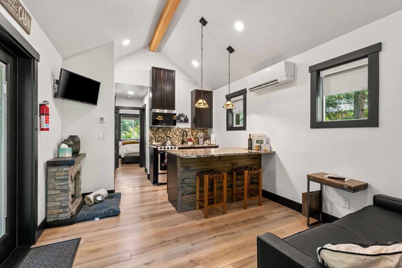 A modern kitchen with a central island, wooden bar stools, and pendant lighting.