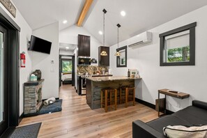 A modern kitchen with a central island, wooden bar stools, and pendant lighting.