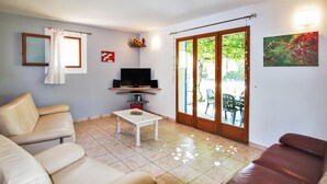 A living room with a TV, two sofas, a coffee table, and a sliding glass door leading to an outdoor area. - Gorgeous home in Carpentras (Carpentras)
