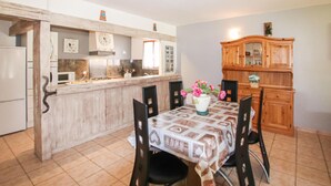 A kitchen with a central island, wooden cabinets, and a dining table with chairs. - Gorgeous home in Carpentras (Carpentras)