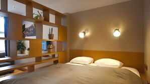 Ein ordentlich eingerichtetes Schlafzimmer mit einem Bett, Holzregalen mit Pflanzen und Wandleuchten.