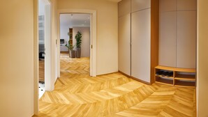 Ein Korridor mit Holzboden, einem Kleiderschrank und einem Schuhregal.
