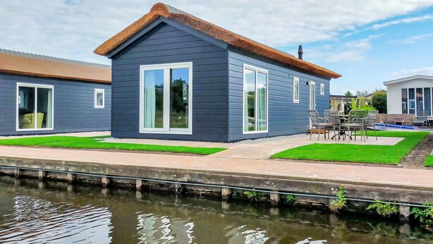 A modern house with a thatched roof, large windows, and a well-maintained lawn. - 2 bedroom amazing home in Giethoorn (Giethoorn)
