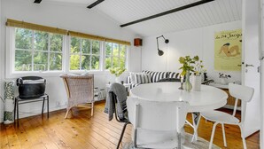 Ein Zimmer mit großem Fenster, weißem runden Tisch und Korbstuhl.