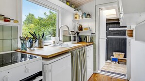Eine kleine Küche mit Fenster, weißen Schränken und einer Holz Arbeitsplatte.