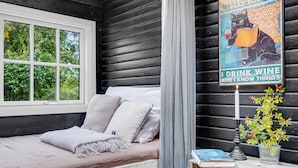 Ein gemütliches Zimmer mit Fenster, einem Bett mit Kissen, einem Poster an der Wand, einer Kerze und einer kleinen Pflanze.