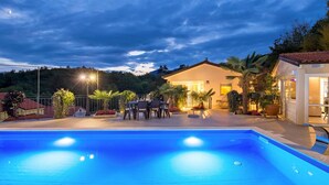 A swimming pool with a patio area, a dining table, and a building with a lighted entrance. - 1 bedroom stunning apartment in Veprinac (Veprinac)