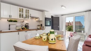 A modern kitchen with white cabinets, a wooden countertop, and a dining area with a table set for four. - 1 bedroom stunning apartment in Veprinac (Veprinac)