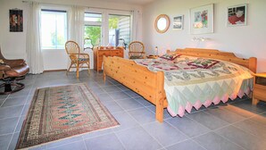 Un dormitorio con una cama de madera, dos sillas, un escritorio y una alfombra.