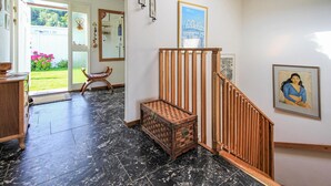 Un pasillo con un banco de madera, un aparador y una escalera.