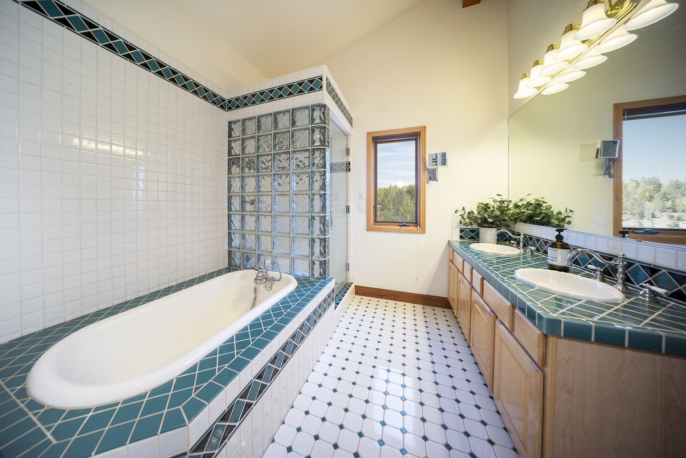 Un baño con una bañera independiente, dos lavamanos y un ventanal.