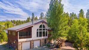Une maison à deux étages avec une façade en pierre, un grand garage et une véranda couverte.