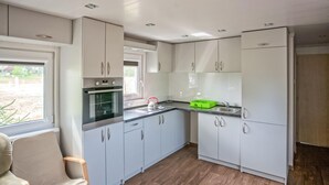 A modern kitchen with white cabinets, a built-in oven, a sink, and a refrigerator.