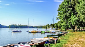 A lakeside dock with various boats moored along the shore.