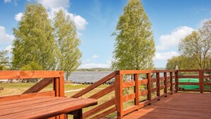 A wooden deck with benches overlooking a lake, surrounded by trees.