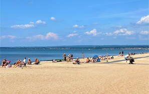 A beach with people sunbathing and swimming, a clear sky, and a distant view of a town across the water. - 2 bedroom pet friendly home in ängelholm (Ängelholm)