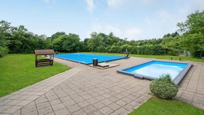 A backyard with two swimming pools, a wooden bench, and a small table.