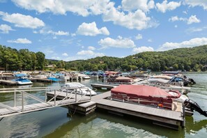 A marina with multiple boats docked at wooden piers, surrounded by a forested hillside. - Knotty by Nature - Hot tub, fire pit, dog friendly, Rumbling Bald Resort Amenities (Lake Lure)