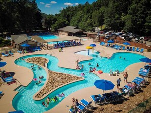 A large outdoor swimming pool with multiple lanes and a separate water slide area. - Knotty by Nature - Hot tub, fire pit, dog friendly, Rumbling Bald Resort Amenities (Lake Lure)