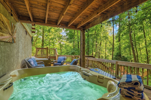 Ein Whirlpoolbereich mit Holzterrasse und Sesseln, umgeben von einem Wald.