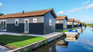 A row of thatched-roof cottages with a narrow waterway in the background. - Beautiful home in Giethoorn with WiFi (Giethoorn)